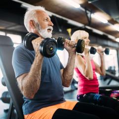 Older man and woman exercising with weights.
