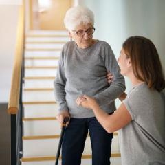 Young lady helping elderly lady down some stairs.
