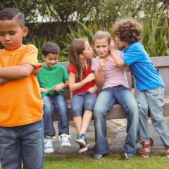 Child being gossiped about by others behind his back.