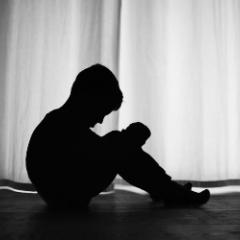 Silhouette of a child sitting in darkness  