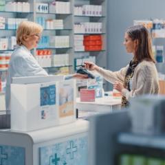 Female pharmacist and young woman buying medication at pharmacy counter