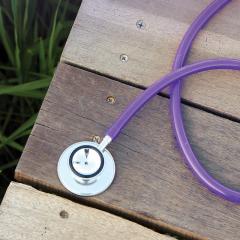 Stethoscope on wooden table over grass