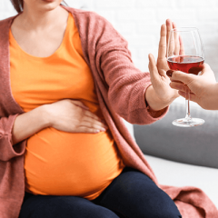 Pregnant woman refusing glass of alcohol