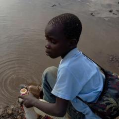 Image of boy filling water bottle from polluted stream