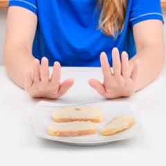 A woman puts her hands up to reject bread