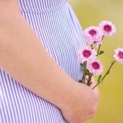 pregnant lady holding flowers beside her belly