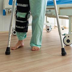 Adobe stock image of lower part of a person on crutches with one leg in a brace