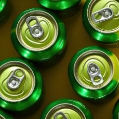 Greens cans of drinks on a yellow surface