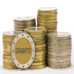 Coins stacked with one facing forward saying the word "grants"