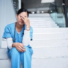 Healthcare worker sitting with their face in their hand