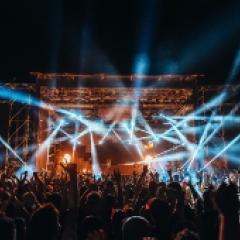 A music festival with a light show and patrons' hands in the air 